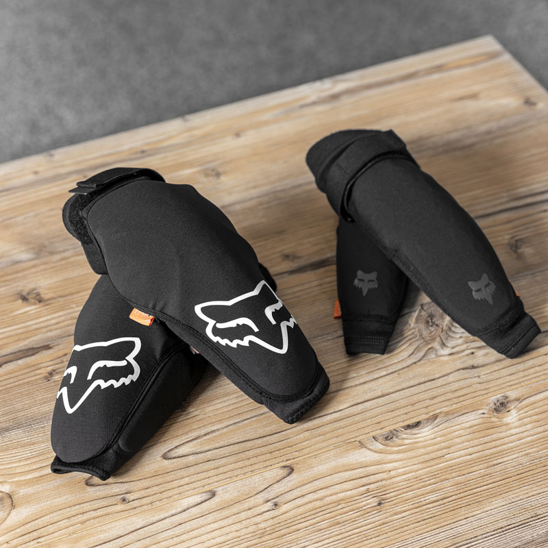 Ellenbogen- & Knieschoner mit weißem Fuchslogos auf Holzoberfläche.