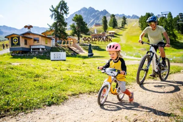 Familien-Radtour: Genießen Sie das Radfahren mit Ihren Lieben auf einem sonnigen Weg in einem malerischen Bergpark.