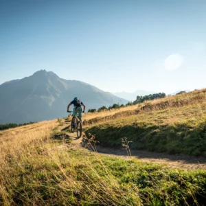 Borderless mountain bike tour on a dirt track with grassy hills and mountains in the background.