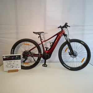 A red mountain bike with a price sign beside it, displayed against a plain background.