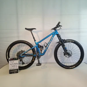 Blaues Pivot Switchblade-Fahrrad mit einem Preisschild von 3.000 € auf einfarbigem Hintergrund.