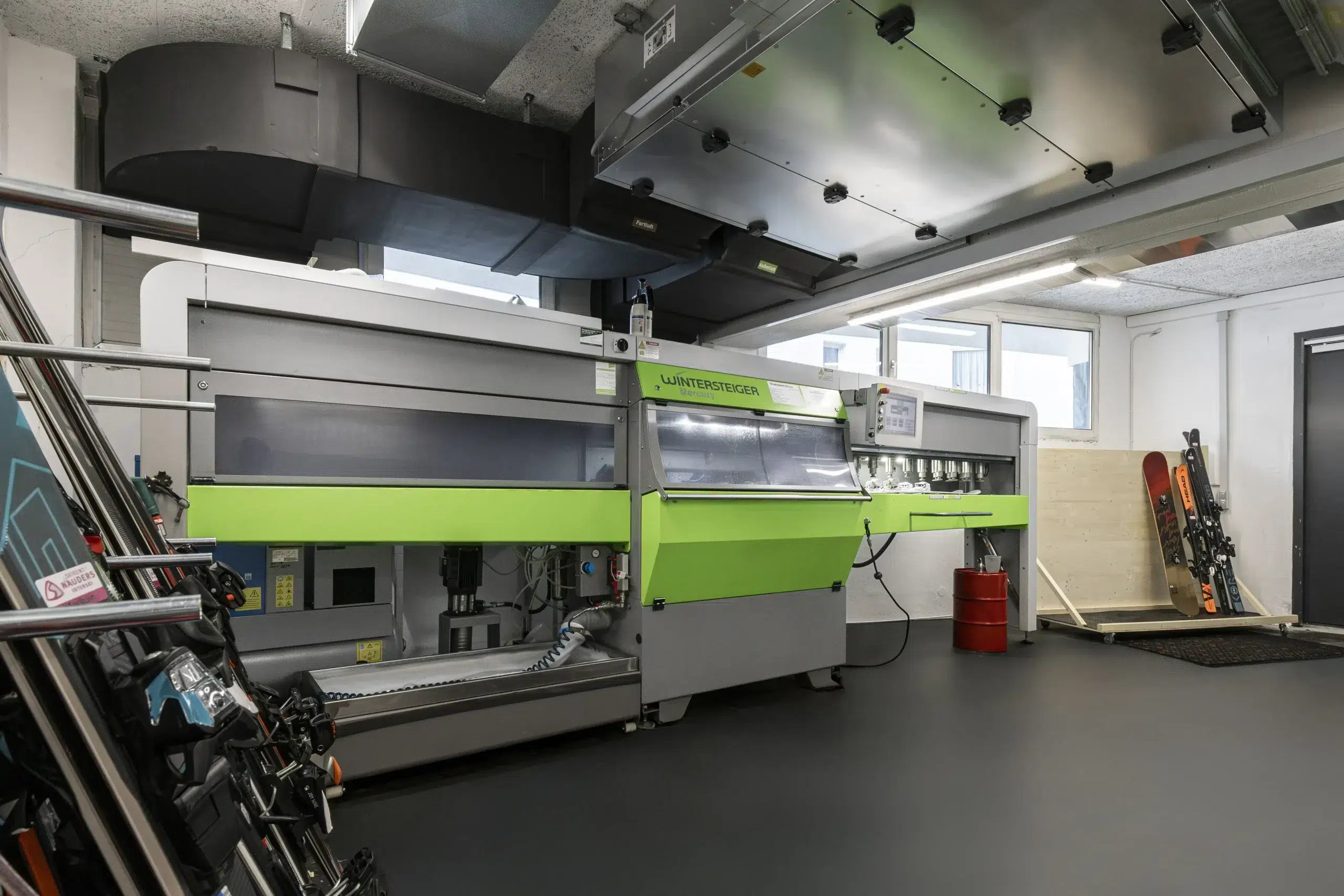 Grüne Skituning-Maschine in einer Werkstatt, in der die Skier aufgestützt sind.