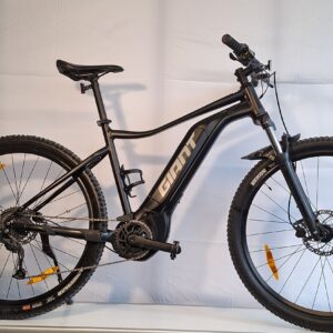 Giant Talon E + 2 Mountainbike mit Scheibenbremsen von einem weißen Info-Schild auf einem Ständer gezeigt.