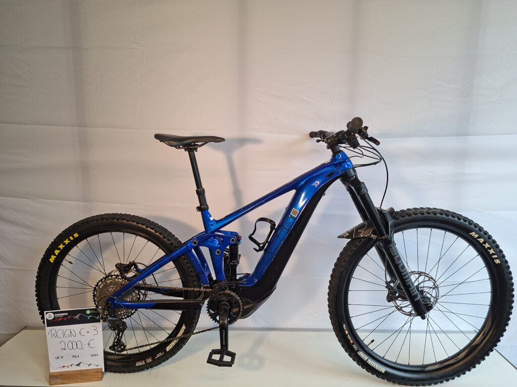 Blaues Mountainbike im Innenbereich, Preisschild mit der Aufschrift Giant Reign E + 3 2000€ daneben.
