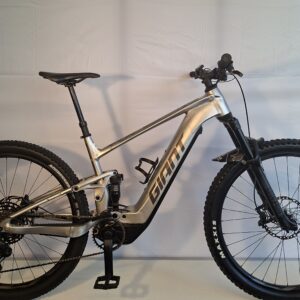 Silbernes Giant-Mountainbike mit dicken Reifen, das in einem Innenraum vor einem weißen Hintergrund ausgestellt ist.