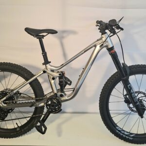 Ein silbernes Mountainbike Faith 24 mit dicken Reifen steht neben einem Schild mit der Aufschrift FAITH 24.